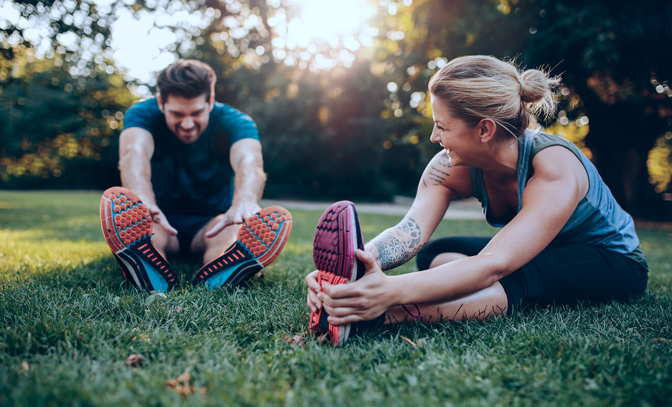 Miniatyyrikuva kahdesta henkilöstä venyttelemässä ulkona ja nauramassa – aktiivinen elämäntapa astmasta huolimatta.